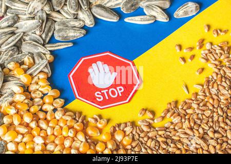 Grani di grano, mais e semi di girasole sulla bandiera gialla e blu dell'Ucraina con segno di stop, crisi di grano ucraino, concetto globale di crisi della fame Foto Stock