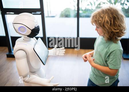 il bambino concentrato interagisce con l'intelligenza artificiale del robot, la comunicazione Foto Stock