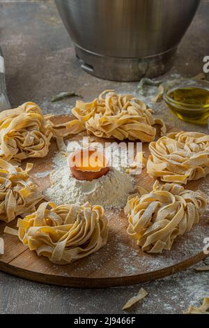 Tagliatelle appena fatte con uova e farina su tavola di legno Foto Stock