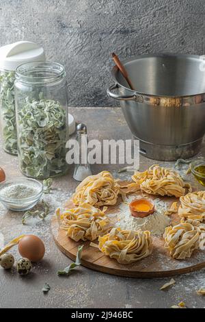 Tagliatelle appena fatte con uova e farina su tavola di legno Foto Stock