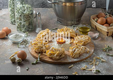 Tagliatelle appena fatte con uova e farina su tavola di legno Foto Stock