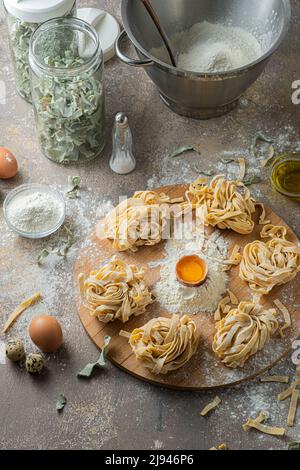 Tagliatelle appena fatte con uova e farina su tavola di legno Foto Stock
