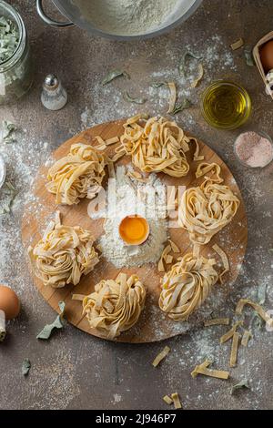 Tagliatelle appena fatte con uova e farina su tavola di legno Foto Stock