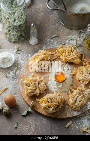 Tagliatelle appena fatte con uova e farina su tavola di legno Foto Stock