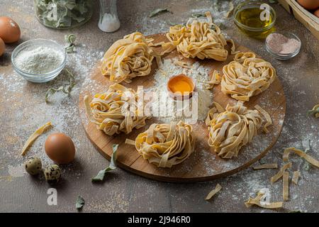 Tagliatelle appena fatte con uova e farina su tavola di legno Foto Stock