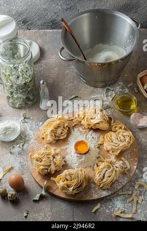 Tagliatelle appena fatte con uova e farina su tavola di legno Foto Stock