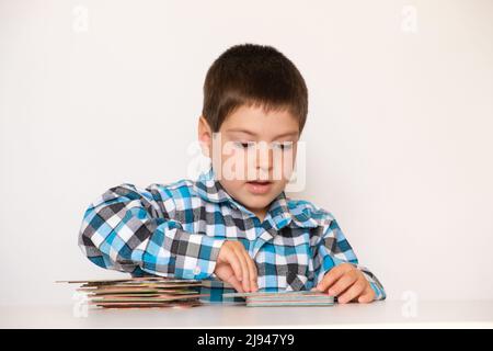 Un ragazzo di 4 anni gioca con carte con immagini, materiale didattico per bambini in età prescolare. Foto Stock