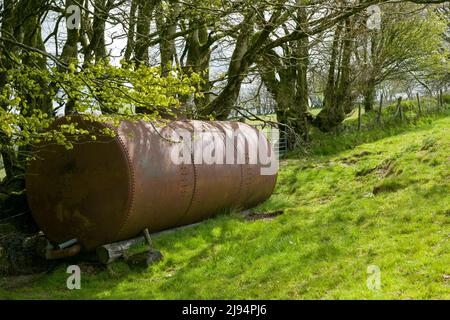 Un vecchio serbatoio agricolo sul bordo di un campo vicino ad un hedgebank di faggio nelle colline di Brendon, Parco Nazionale di Exmoor, Somerset, Inghilterra. Foto Stock