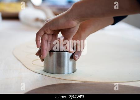 Donna che lavora all'interno di una fabbrica di pasta o di un ristorante e che stampa ravioli freschi, culurgiones, agnolotti. Pasta fresca fatta in casa Foto Stock