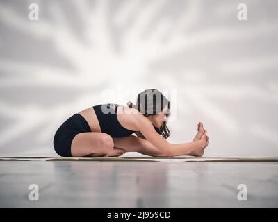 Una giovane donna cacucasiana, che esercita yoga in varie posizioni e asanas. Girato in studio su sfondo bianco. Foto Stock