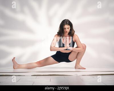 Una giovane donna cacucasiana, che esercita yoga in varie posizioni e asanas. Girato in studio su sfondo bianco. Foto Stock