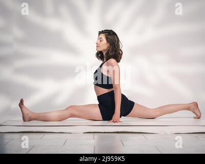 Una giovane donna cacucasiana, che esercita yoga in varie posizioni e asanas. Girato in studio su sfondo bianco. Foto Stock