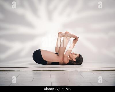 Una giovane donna cacucasiana, che esercita yoga in varie posizioni e asanas. Girato in studio su sfondo bianco. Foto Stock