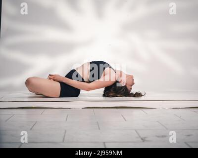 Una giovane donna cacucasiana, che esercita yoga in varie posizioni e asanas. Girato in studio su sfondo bianco. Foto Stock