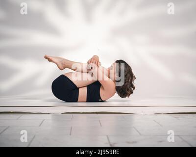 Una giovane donna cacucasiana, che esercita yoga in varie posizioni e asanas. Girato in studio su sfondo bianco. Foto Stock