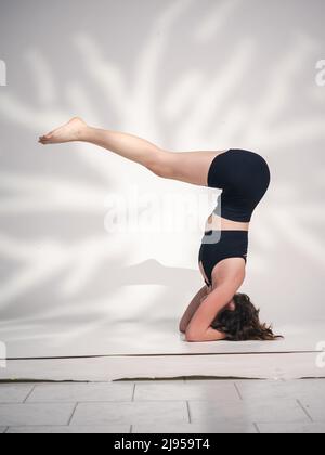 Una giovane donna cacucasiana, che esercita yoga in varie posizioni e asanas. Girato in studio su sfondo bianco. Foto Stock