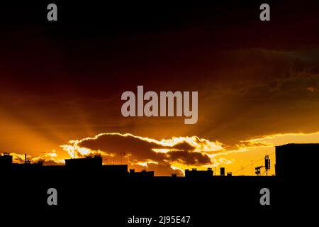 La silhouette dell'edificio cittadino con la torre delle telecomunicazioni al tramonto Foto Stock