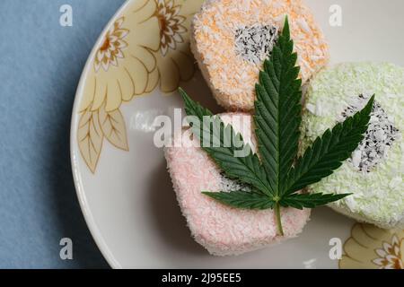 Dessert di cannabis. Delizia turca con fiocchi di cocco su un piatto, vista dall'alto. Foglia di marijuana verde. Composizione di cibo di canapa con olio CBD. Foto Stock