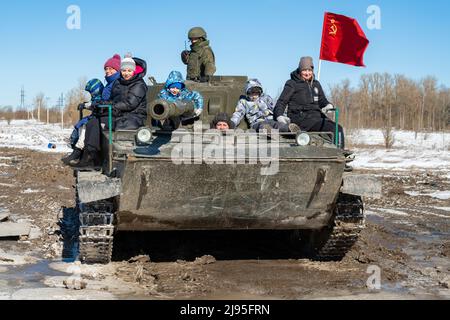 KRASNOE SELO, RUSSIA - 27 MARZO 2022: I visitatori con bambini cavalcano nel carro armato anfibio sovietico di PT-76 in un giorno di marcia soleggiato. Militare Patriotic par Foto Stock