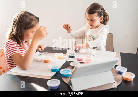 Le bambine scolpiscono le figurine di artigianato da aria plastilina, modeling pasta.Online lezioni in tablet. Creatività dei bambini,hobby,attività di sviluppo,t Foto Stock