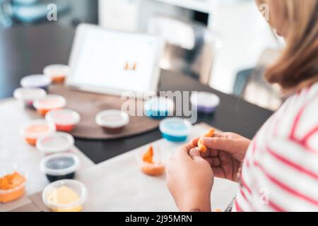 Le bambine scolpiscono le figurine di artigianato da aria plastilina, modeling pasta.Online lezioni in tablet. Creatività dei bambini,hobby,attività di sviluppo,t Foto Stock