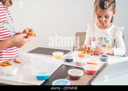 Le bambine scolpiscono le figurine di artigianato da aria plastilina, modeling pasta.Online lezioni in tablet. Creatività dei bambini,hobby,attività di sviluppo,t Foto Stock