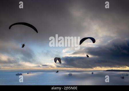 Parapendio che sorvolano le navi da crociera ancorate a Weymouth Bay, con Portland Beyond, Dorset, Inghilterra, Regno Unito Foto Stock