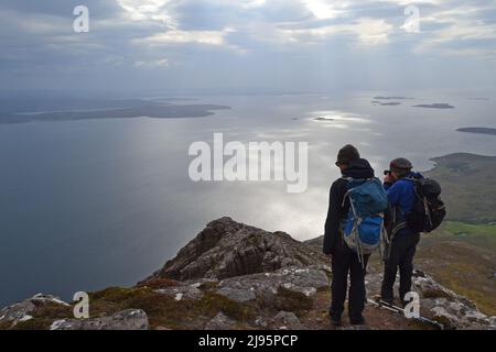 Escursionisti/escursionisti in collina con silhouette su ben Mor Coigach, una cresta vicino Ullapool, Scozia nord-occidentale, Assynt, ammirare le viste delle isole estive in una giornata di primavera Foto Stock