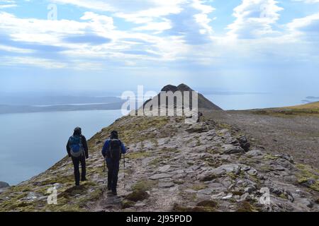 Escursionisti/escursionisti in collina con silhouette su ben Mor Coigach, una cresta vicino Ullapool, Scozia nord-occidentale, Assynt, ammirare le viste delle isole estive in una giornata di primavera Foto Stock