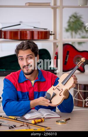 Giovane uomo che ripara gli strumenti musicali all'interno Foto Stock