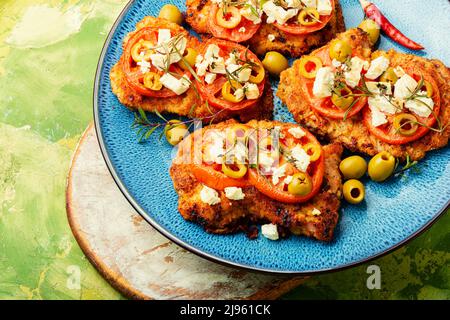 Sottile strato di carne, impanato in pangrattato con formaggio, olive e pomodoro. Piatto di carne - schnitzel Foto Stock