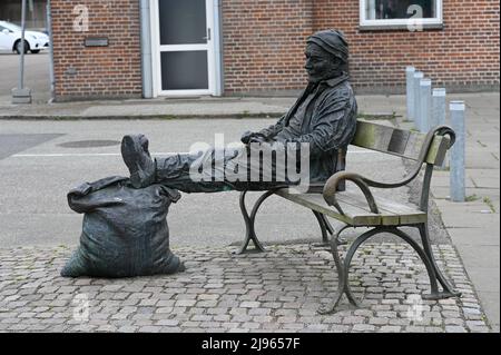 Il 20 maggio 2022 ad Aarhus, in Danimarca, il lavoratore portuale seduto su una panchina con un'ape e i suoi piedi su un sacco pieno. La scultura è creata da Jens Galschiøt. Foto Stock