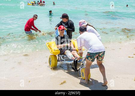 Miami Beach Florida, Sabrina Cohen Adaptive Beach Day, disabili esigenze speciali disabili waterwheels galleggianti sedia a rotelle, uomo ispanico donna maschile Foto Stock