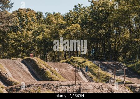 Vista ad angolo elevato di una pista da motocross. Sul lato destro della pista un motociclista salta. Spazio di copia. Concetto di motocross, sport estremi. Foto Stock