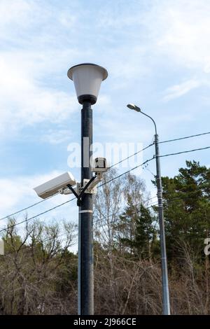 Telecamere di sorveglianza montate su un lampione sul lato di una strada forestale. Telecamera cctv di sicurezza. Sicurezza in città. Riprese nascoste di ciò che è happeni Foto Stock