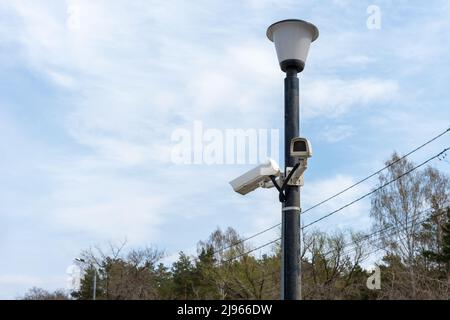 Telecamere di sorveglianza montate su un lampione sul lato di una strada forestale. Telecamera cctv di sicurezza. Sicurezza in città. Riprese nascoste di ciò che è happeni Foto Stock