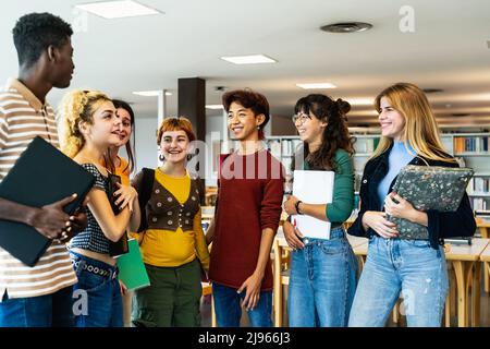 Giovani studenti universitari in piedi all'interno della biblioteca - concetto di educazione scolastica Foto Stock