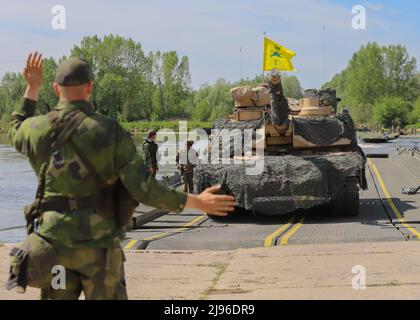 Un soldato svedese guida un M1A1 Abrams Tank assegnato al Battaglione 1st, 66th Armored Regiment, 3rd Armored Brigade Combat Team, 4th Infanteria Divisione, mentre attraversa il Vistula River Wet Gap come parte del Defender Europe a DĘBLIN, Polonia, 13 maggio 2022. Defender Europe 22 è una serie di esercizi di addestramento multinazionale dell'Esercito degli Stati Uniti in Europa e Africa nell'Europa dell'Est. L’esercizio dimostra la capacità dell’Esercito americano Europa e dell’Africa di condurre operazioni di combattimento a terra su larga scala in più sale cinematografiche a sostegno della NATO. (STATI UNITI Esercito foto di SPC. Devin Klecan) Foto Stock