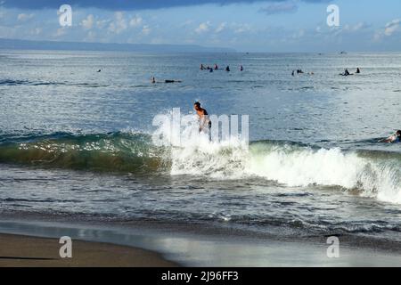 Un giovane surfista che cavalca un'onda a Batu Bolong Beach a Canggu, Bali, Indonesia Foto Stock