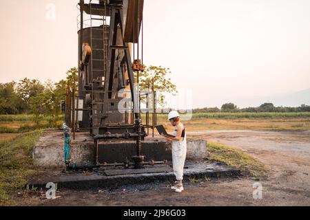 Ingegneria petrolchimica asiatica donna con casco di sicurezza in piedi nella struttura petrolifera industria petrolchimica. Foto Stock