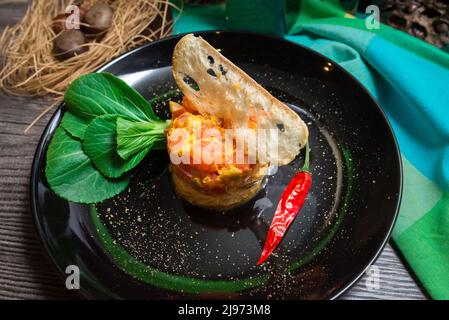 Scaloppa di pollo con pomodoro piccante e salsa di olive. Decorato con sottile fetta di crostini, peperoncino su un lato, fresco pak choi giovane. Insalata ci ring Foto Stock