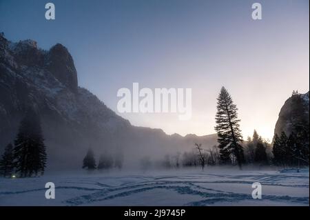 La valle di Yosemite è circondata da un sottile strato di nebbia che si estende sul fiume merced, fornendo un'atmosfera inquietante intorno al tramonto. Foto Stock