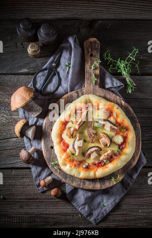 Pizza gustosa con pomodori, funghi e formaggio. Pizza funghi fatti in casa con formaggio ed erbe. Foto Stock