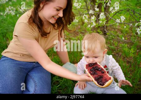 madre e figlia mangiano il pane della marmellata in una sorgente di picnic Foto Stock