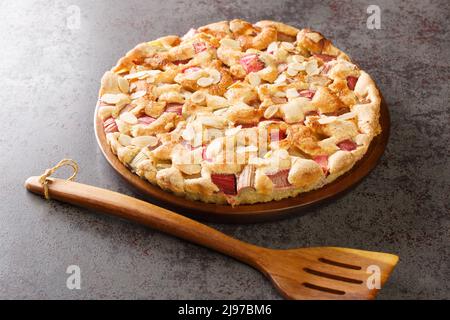 Torta tradizionale di rabarbaro fresco con le mandorle in primo piano in un piatto sul tavolo. Orizzontale Foto Stock