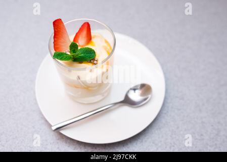 Parfait alla fragola con salsa di mango decorato con foglie di menta Foto Stock