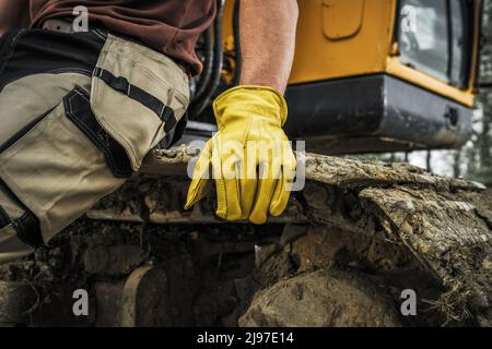 Operatore bulldozer appoggiato su un cingolo Caterpillar in primo piano. Macchine per impieghi pesanti, lavori di movimentazione al suolo. Foto Stock