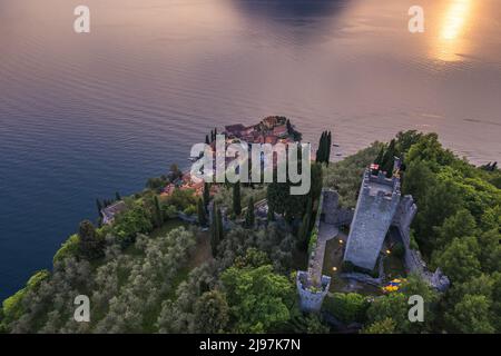 Veduta aerea del Castello di Vezio e del borgo di Varenna sullo sfondo durante il tramonto estivo. Fuco girato nel lago di Como. Varenna, Italia Foto Stock