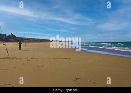 Tranquilla scena di spiaggia di sabbia mattina con poche persone, bassa marea, canne da pesca pescatore, cielo blu, onde di mare - Zahara de los Atunes, Costa de la Luz, Spagna Foto Stock