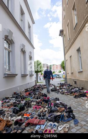 Ostritz, Germania. 21st maggio 2022. Un uomo cammina davanti a molte scarpe all'Ostritzer Friedensfest. Le scarpe si trovano lì per rappresentare le persone che hanno perso la vita in mare. Il Friendensfest è stato parte integrante della comunità per anni per opporsi a eventi orientati alla destra nella città. Credit: Daniel Schäfer/dpa/Alamy Live News Foto Stock